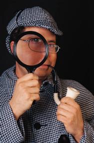 color photo of a Sherlock Holmes look-alike with deerstalker hat, magnifying glass and curved meerschaum pipe